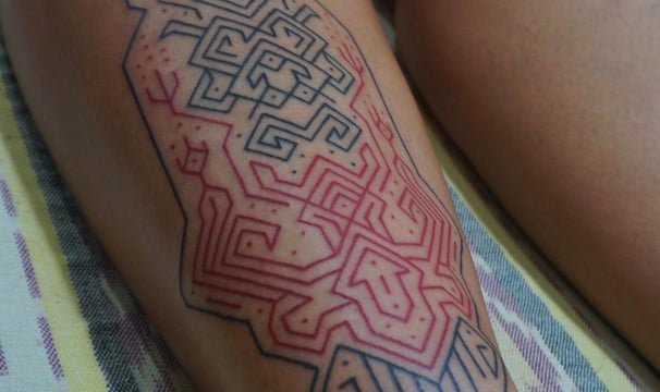 An handpoke tattoo featuring art ornaments symmatrical geomatric lines tappis hand weaving inspired.