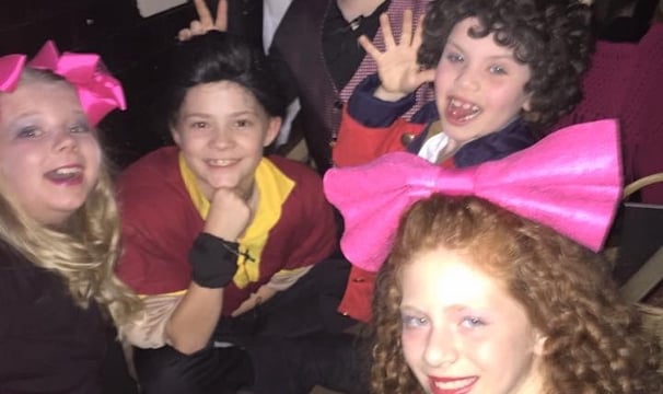 a group of kid actors posing for a picture backstage connecting as friends.