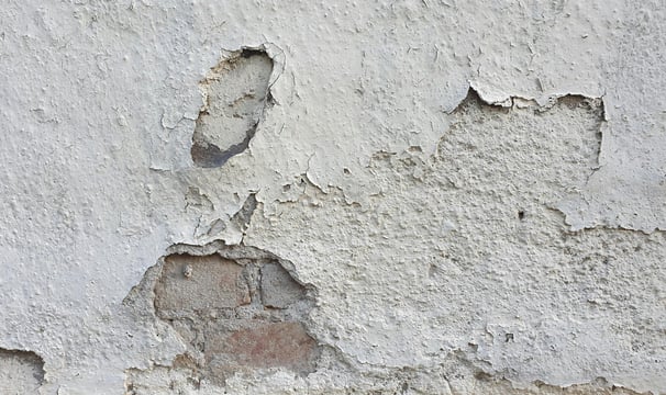 Application d'enduit sur un mur abîmé pour une rénovation complète, réalisée par L'Atelier BERNARD