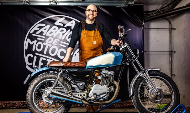 a man in overalls and overalls standing next to a motorcycle