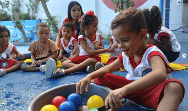 Crianças da educação infantil sentadas realizando atividades lúdicas