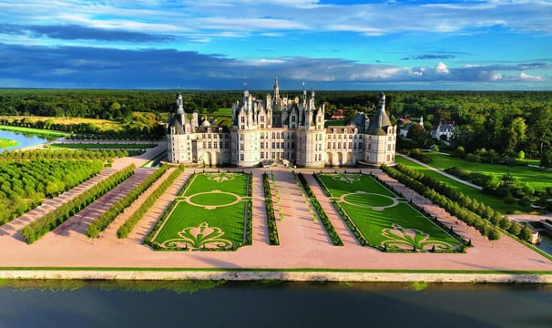 a castle like building with a large lawn and a lake