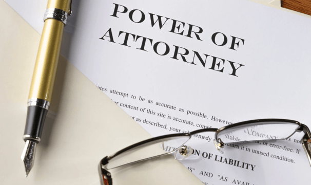 Power of attorney document with pen and glasses, symbolizing legal financial authority.