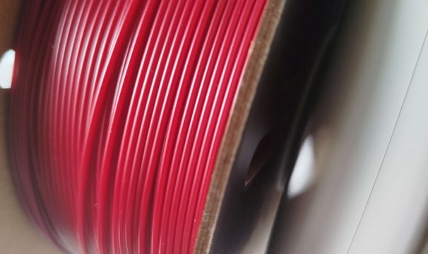 Spool of dark red 3D printing filament on AMS