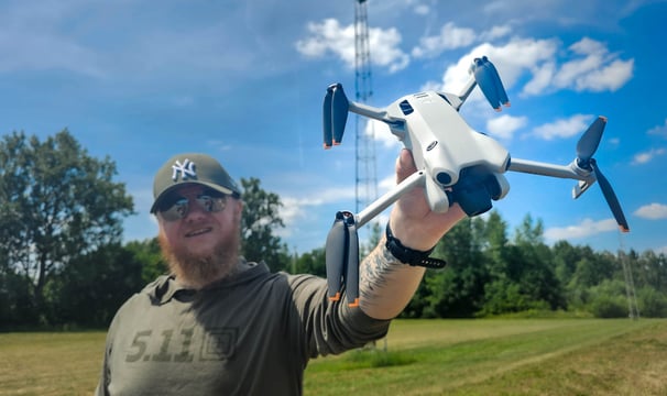 Dronepiloot toont DJI Mini 4 Pro drone in open veld tijdens voorbereidingen voor luchtinspectie op locatie