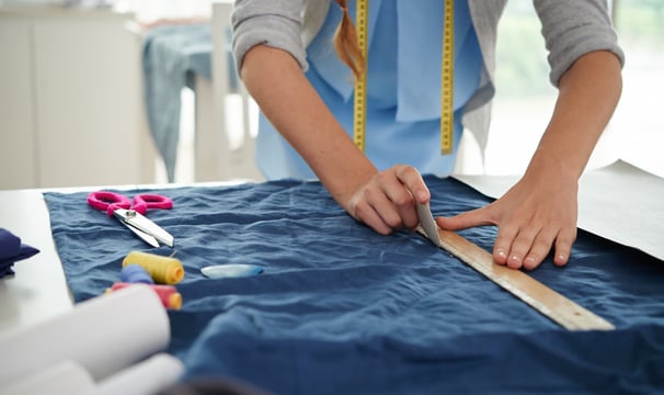 Señora marcando un trozo de tela para realizar un corte y crear una prenda de ropa