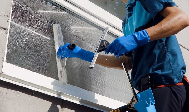 a man in blue gloves and gloves is cleaning a window