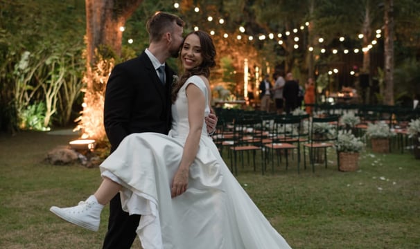 Casal de noivos em cerimônia ao ar livre; a noiva veste um vestido exclusivo do Ateliê Moncheri