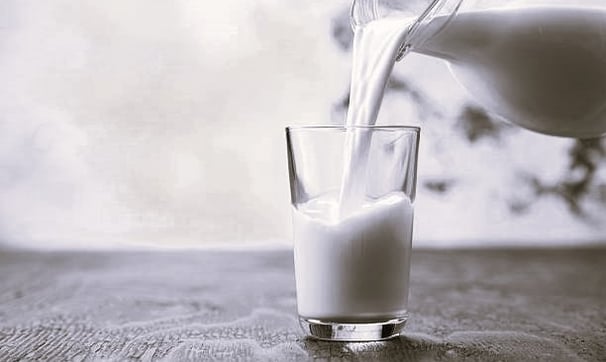 a pitcher of milk being poured into a glass