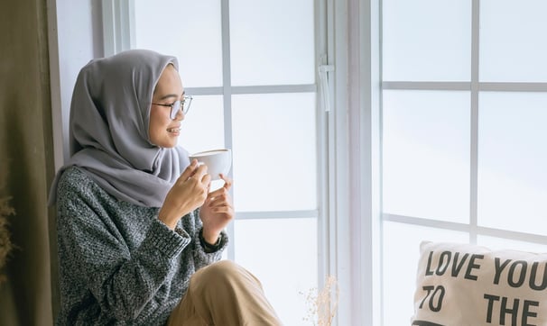 A beautiful girl with Good daily habits for better mental health enjoying her coffee by the window