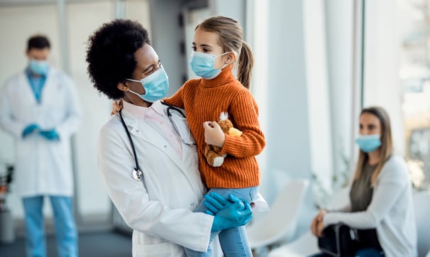 Médica sorrindo com uma menina no colo