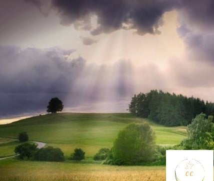 paysage surfait d'un ciel nuageux violet laissant passer ds rayons du soleil qui viennent illuminer la plaine verdoyante,
