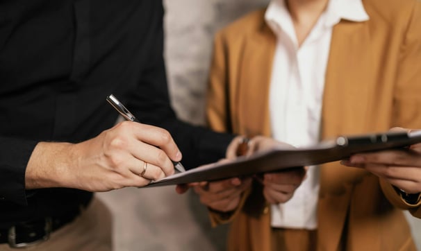 un hombre y una mujer sujetando un portapapeles y escribiendo en él