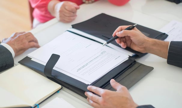 un hombre y una mujer sentados a una mesa con un contrato
