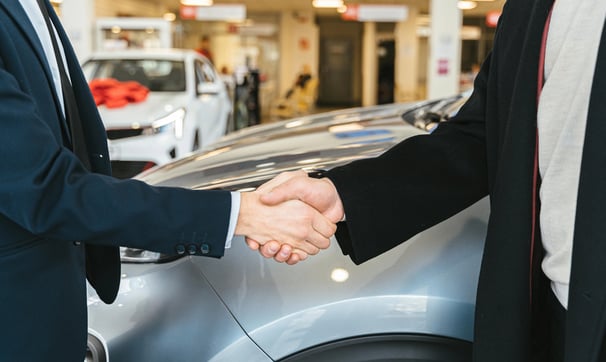 dos hombres se dan la mano en un concesionario de coches