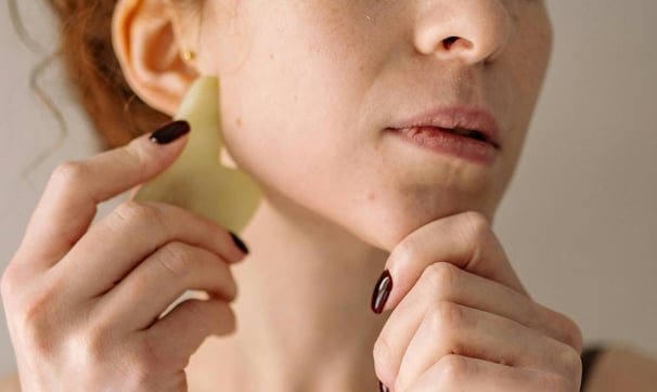 A woman using a gua sha as part of her regular step-by-step skincare routine