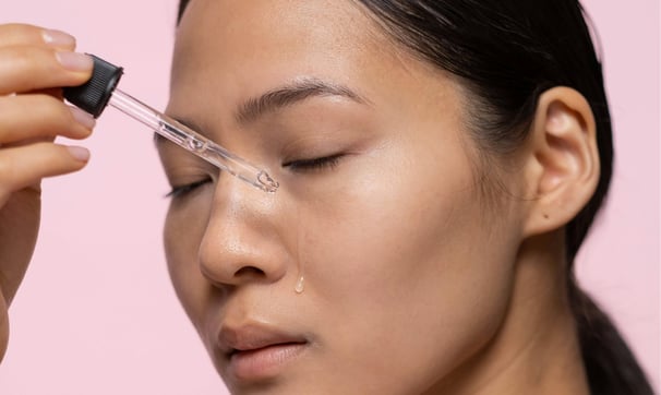Asian woman applying serum on her face