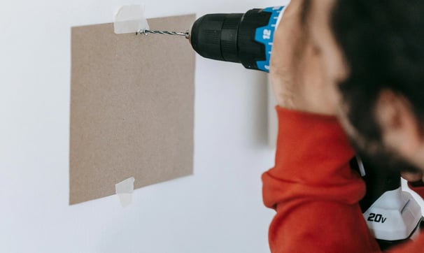 un hombre utiliza un taladro para instalar un muro