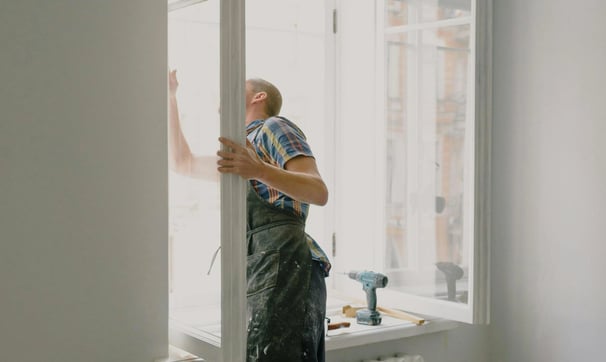 un hombre con mono de trabajo está pintando una ventana