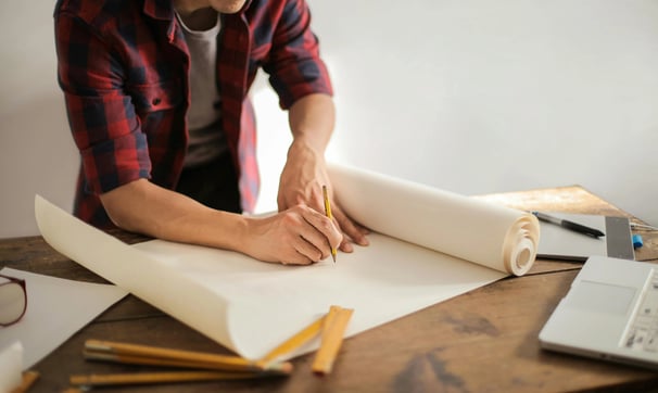 un hombre sostiene un rollo de papel y un lápiz