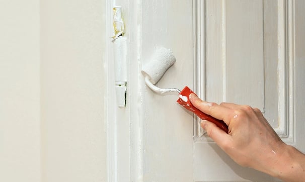 una persona que pinta una puerta con un rodillo