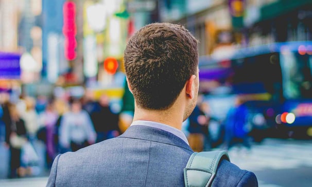 a man in a suit and a backpack on a city street