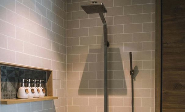 Walk-in shower with matte black fixtures and recessed shelf on subway-tiled wall