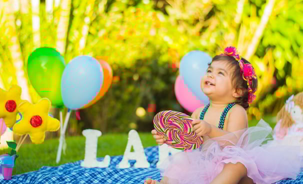 Petite fille assise dans un jardin sourit et regarde en haut - Micro-crèche ou assistante maternelle