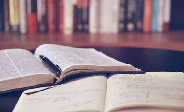 Book open with pen on top of notebook with writing