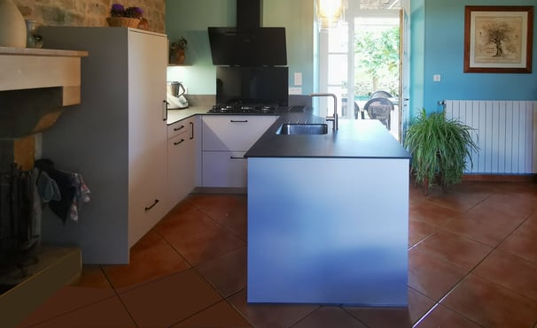 Cuisine beige et plan de travail pierre. Cuve inox, hotte murale, plaque cuisson gaz. Ilot central.