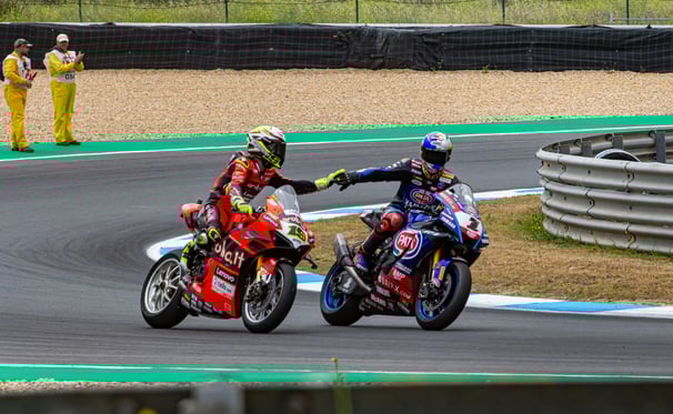 due motociclisti che si danno la mano, moto rosa e blu