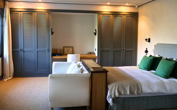 Elegant bedroom with Hamptons-style wardrobes, botanical mural, and soft neutral linens