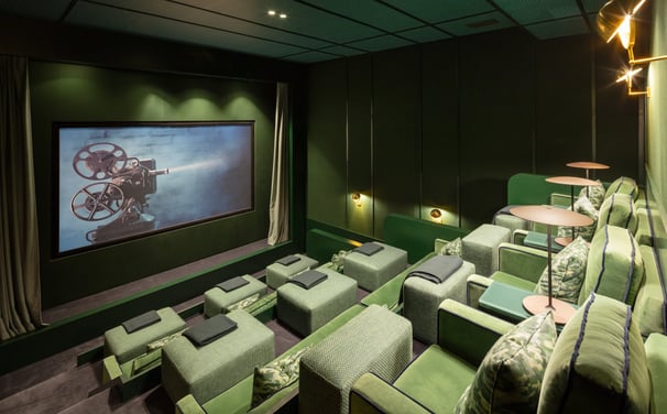Private cinema at Villa La Gratitud with plush green seats, designer lighting, and big screen.