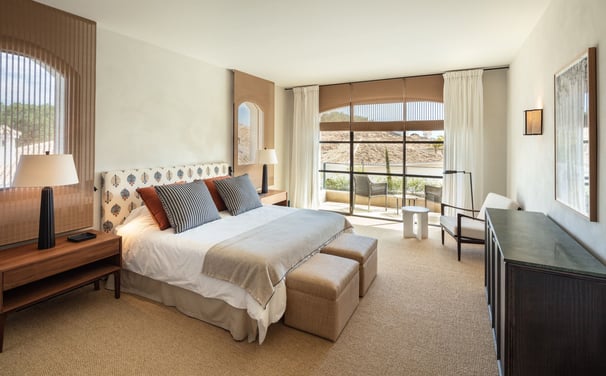 Bright bedroom suite at Villa La Gratitud with garden views, cozy seating, and soft natural tones.