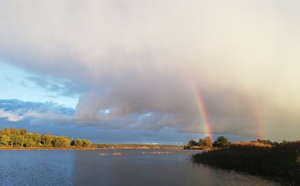 ett vackert svenskt landskap med två regnbågar. en sjö för gäddfiske med fiskeflykt sverige.