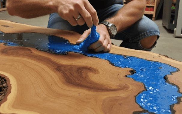 Blue resin epoxy being poured in a live edge wood table with resin epoxy