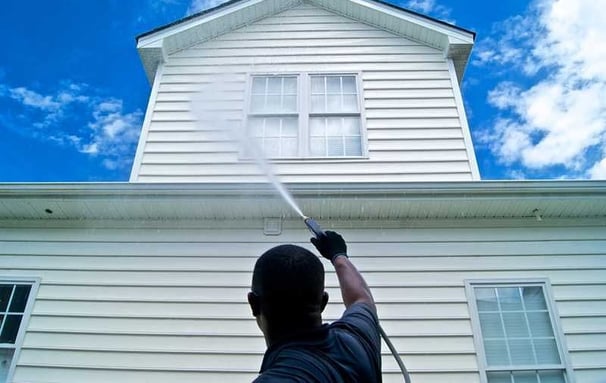 Pressure washing services worker soft washing a vinyl siding house