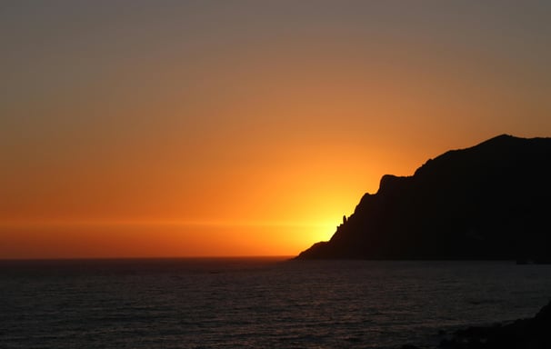 a sunset over the ocean with a boat in the water