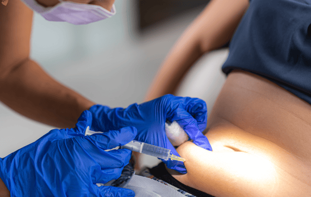 a woman in a blue dress is getting a tattoo on her belly