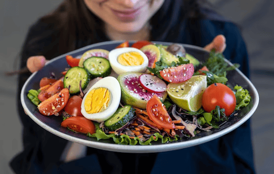 a woman holding a plate with a salad on it