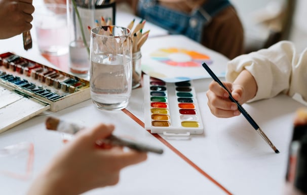 a child's hands holding a paintbrush and a paintbrush