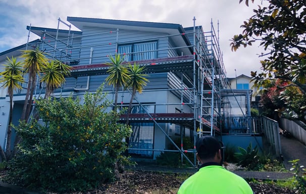 a man in a green shirt standing in front of a house