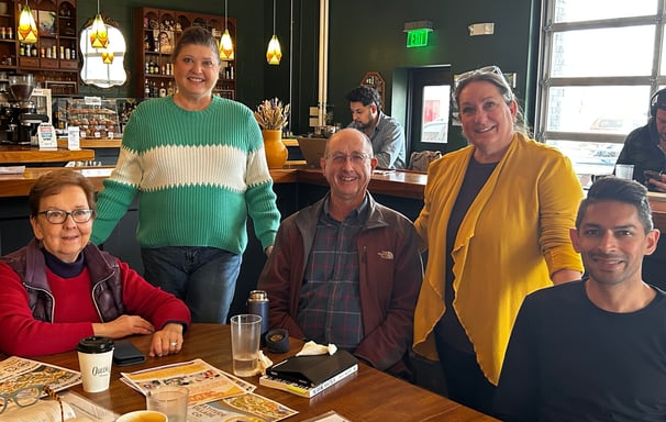 Group of smiling men and women at a table in a coffee house