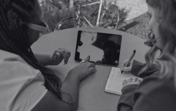 foto preto e branca de mulheres empreendedoras conversando com um tablet na mesa