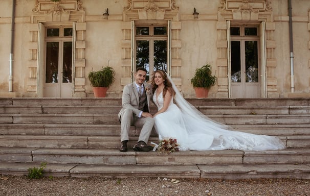 belle photographie des mariées assis sur les marches du château