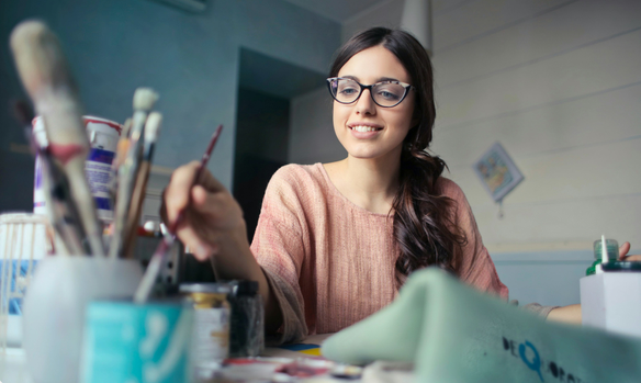 a woman in glasses and a pink sweater is sitting at a desk