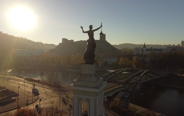 Saulė šviečia į energetikos muziejų Vilniuje, Gedimino pilis tolumoje, drono fotografija