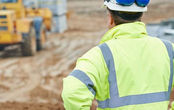 a construction worker in a yellow safety vest and safety glasses