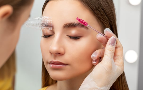 professional brushing clients eyebrow after brow lamination treatment