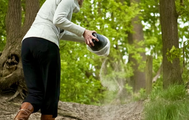 a women scattering ashes in woodlands